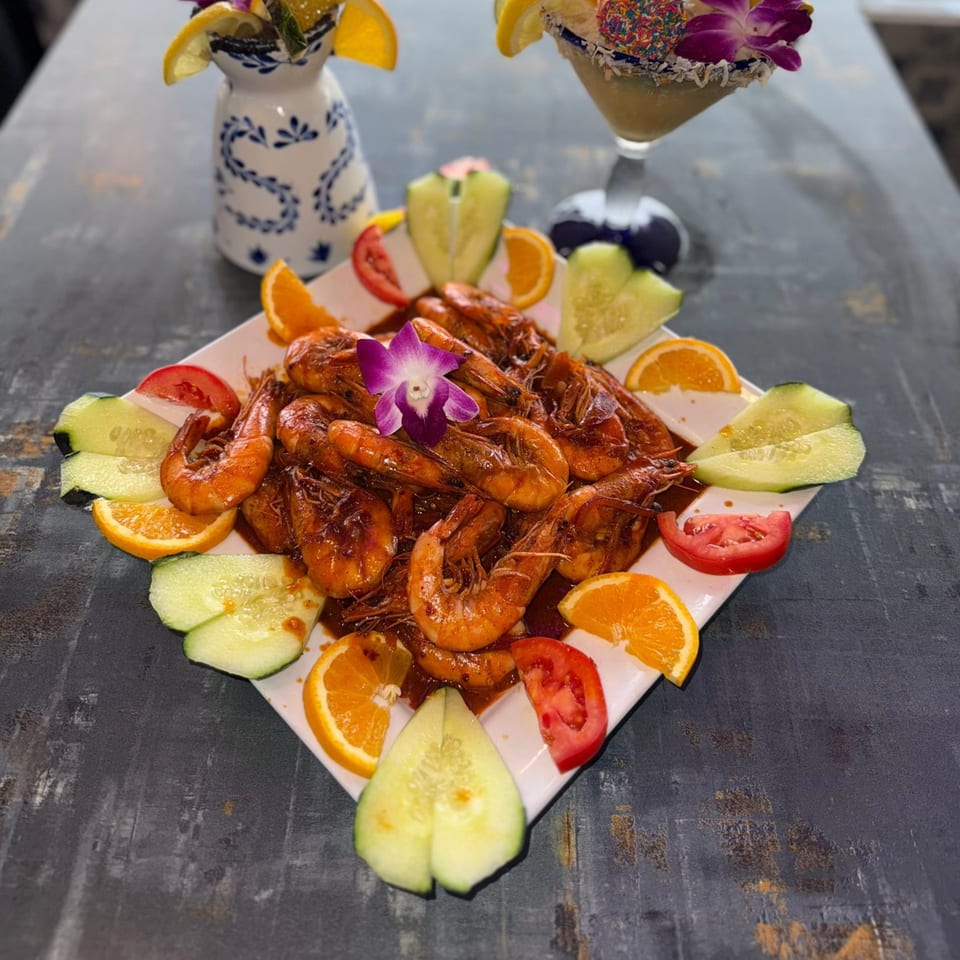 A plate of La Plaza Fiesta's Mexican shrimp dish, garnished with oranges, cucumbers, and tomatoes.